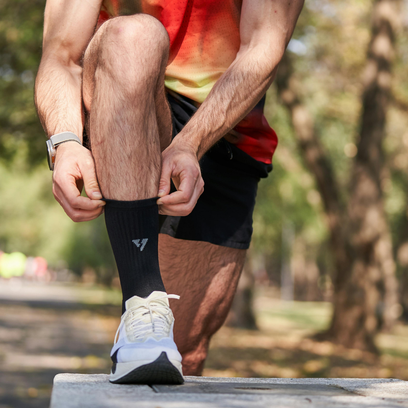 Person tying shoelaces on a bench with a natural background
